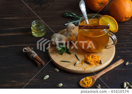 Useful tea with saffron and ginger in a glass mug on a dark wooden background, horizontally Useful tea with saffron and ginger in a glass mug on a dark wooden background, horizontally 65810574