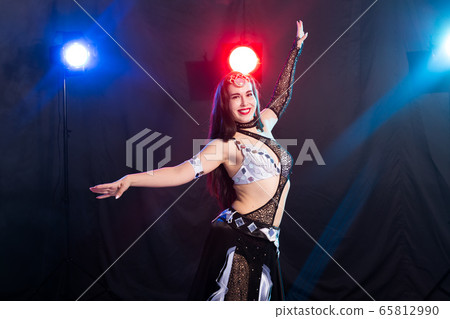 Belly dancer. Young attractive woman dancing tribal fusion on the stage. Oriental exotic dance. Belly dancer. Young attractive woman dancing tribal fusion on the stage. Oriental exotic dance. 65812990