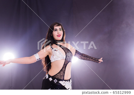 Young woman belly dancer in exotic dress with gold, dancing tribal fusion dance in studio. Young woman belly dancer in exotic dress with gold, dancing tribal fusion dance in studio. 65812999