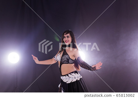 Young woman dancing in Tribal Fusion style. Belly dance on the stage. 65813002