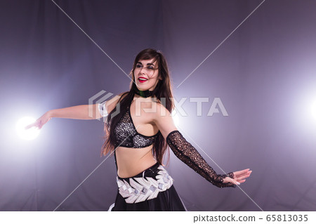 Young woman belly dancer in exotic dress with gold, dancing tribal fusion dance in studio. Young woman belly dancer in exotic dress with gold, dancing tribal fusion dance in studio. 65813035
