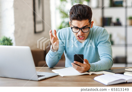 Angry ethnic freelancer reading message on 65813149