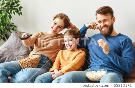 Happy family resting with snacks on couch at home. Happy family resting with snacks on couch at home. 65813171