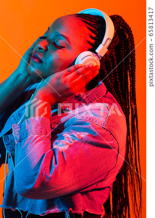 Neon portrait of young african woman listening music with earphones. Neon portrait of young african woman listening music with earphones. 65813417