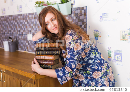 Young red-haired woman relaxing at home with books. Quarantine, isolation, coronavirus pandemic world. Stay at home. 65813840