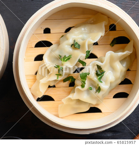 Gyozas potstickers chinese dumplings in wooden steamer with soy sauce fresh herbs and chopsticks on old wood tabletop view overhead close up Gyozas potstickers chinese dumplings in wooden steamer with soy sauce fresh herbs and chopsticks on old wood tabletop view overhead close up 65815957