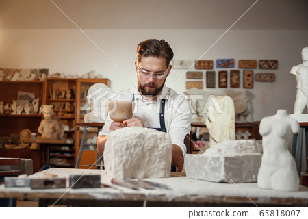 Stone carver works with wooden hammer and chisel at limestone. Stone carver works with wooden hammer and chisel at limestone. 65818007