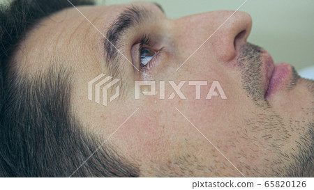 High quality close-up of a man laying on a couch and crying during the treatment. Male tears closeup video. High quality close-up of a man laying on a couch and crying during the treatment. Male tears closeup video. 65820126