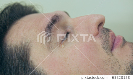 High quality close-up of a man laying on a couch and crying during the treatment. Male tears closeup video. High quality close-up of a man laying on a couch and crying during the treatment. Male tears closeup video. 65820128