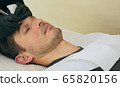 Close up of cosmetologist making permanent makeup. Microblading procedure. High quality close-up of a man laying on a couch during the esthetician brow microblading treatment. 65820156