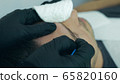 Close up of cosmetologist making permanent makeup. Microblading procedure. High quality close-up of a man laying on a couch during the esthetician brow microblading treatment. 65820160