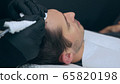 High quality close-up of a man laying on a couch during the esthetician hair treatment. Male tricopigmentation service. Scalp micropigmentation treatment. Trichopigmentation procedure. 65820198