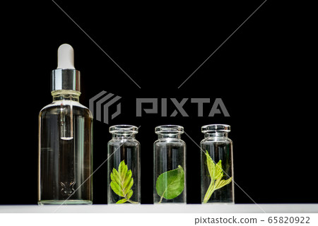 Homeopathic oil, serum and bottles with plants on blblack background Homeopathic oil, serum and bottles with plants on blblack background 65820922
