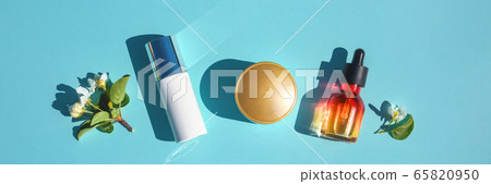 Set of beauty products flat lay on a blue background. The concept of natural cosmetics. Serum, cream skin care, minimal Set of beauty products flat lay on a blue background. The concept of natural cosmetics. Serum, cream skin care, minimal 65820950