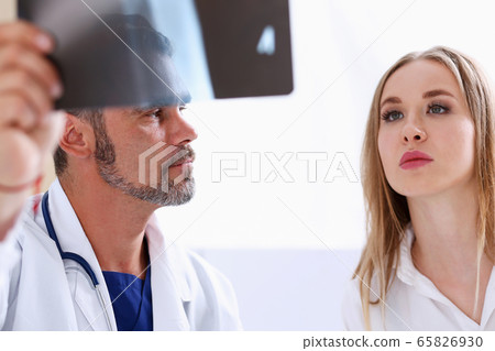 Mature male doctor hold in arm and look at xray photography Mature male doctor hold in arm and look at xray photography 65826930
