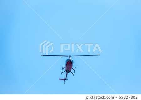 A small helicopter flies in a clear blue sky. A small helicopter flies in a clear blue sky. 65827802