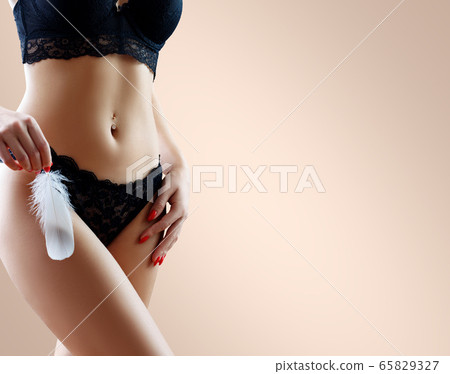Woman holds the feather over hips background. 65829327