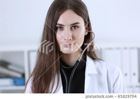 Beautiful smiling female doctor sit at workplace. Beautiful smiling female doctor sit at workplace. 65829704