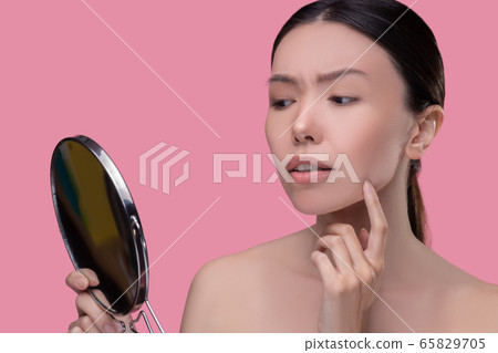 Worried dark-hairfed asian girl looking and the mirror Worried dark-hairfed asian girl looking and the mirror 65829705