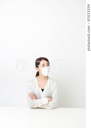 戴著面具和雙臂交叉坐著的女人 戴著面具和雙臂交叉坐著的女人 65833204