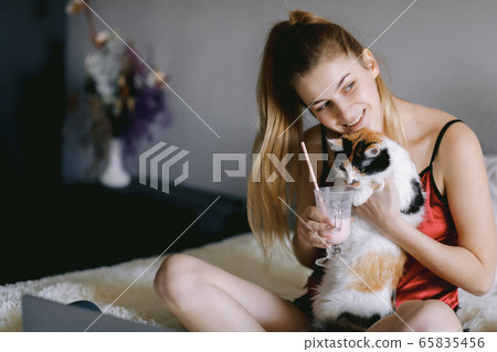 Young student drinking milkshake and playing with cat 65835456