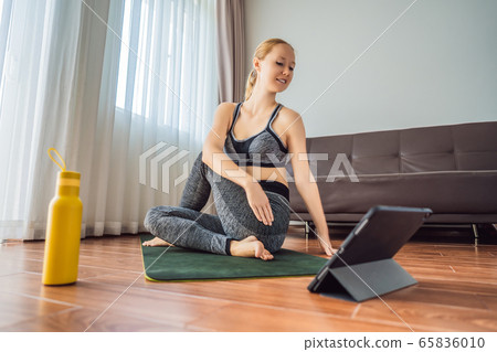 Fitness woman exercising on the floor at home and watching fitness videos in a tablet. People do Fitness woman exercising on the floor at home and watching fitness videos in a tablet. People do 65836010