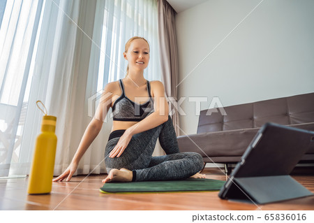 Fitness woman exercising on the floor at home and watching fitness videos in a tablet. People do Fitness woman exercising on the floor at home and watching fitness videos in a tablet. People do 65836016