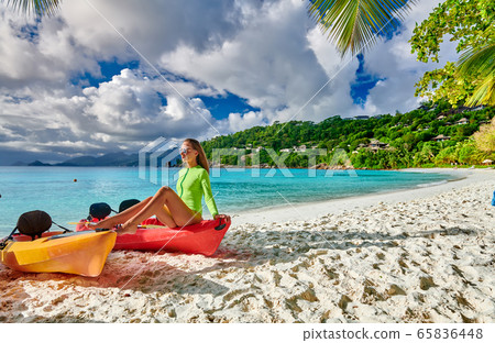 Woman sitting on kayak at beach, Seychelles, Mahe 65836448
