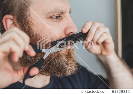 Man cutting moustache and beard himself at home 65839813