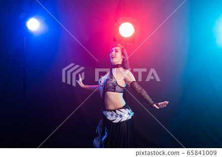 Young woman belly dancer in exotic dress with gold, dancing tribal fusion dance in studio. Young woman belly dancer in exotic dress with gold, dancing tribal fusion dance in studio. 65841009