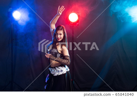 Young woman belly dancer in exotic dress with gold, dancing tribal fusion dance in studio. Young woman belly dancer in exotic dress with gold, dancing tribal fusion dance in studio. 65841040