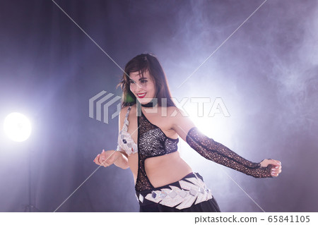Young woman belly dancer in exotic dress with gold, dancing tribal fusion dance in studio. 65841105