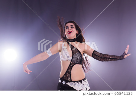 Young woman belly dancer in exotic dress with gold, dancing tribal fusion dance in studio. 65841125