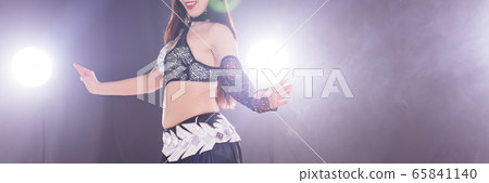 Young woman belly dancer in exotic dress with gold, dancing tribal fusion dance in studio. Copy space, close-up. Young woman belly dancer in exotic dress with gold, dancing tribal fusion dance in studio. Copy space, close-up. 65841140