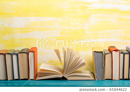 Composition with vintage old hardback books, diary, fanned pages on wooden deck table and abstract background. Books stacking. Back to school. Copy Space. Education background. 65844622