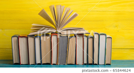 Composition with vintage old hardback books, diary, fanned pages on wooden deck table and abstract background. Books stacking. Back to school. Copy Space. Education background. Composition with vintage old hardback books, diary, fanned pages on wooden deck table and abstract background. Books stacking. Back to school. Copy Space. Education background. 65844624