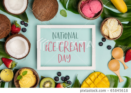 National ice cream day 19 july concept. Tropical fruits and plants with variety of ice cream in coconut shells on blue background 65845618