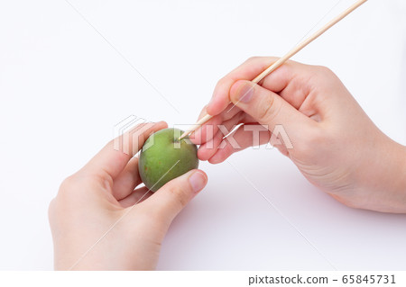 Ome making plum wine, remove the stale attached to the plum fruit with a bamboo skewer Ome making plum wine, remove the stale attached to the plum fruit with a bamboo skewer 65845731