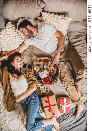 Happy smiling couple lying in bed and having Happy smiling couple lying in bed and having 65846612