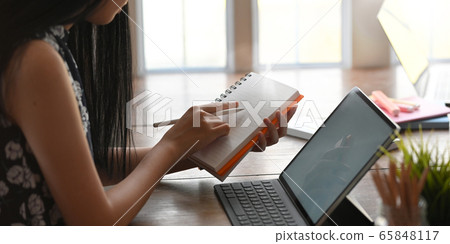 Cropped of young entrepreneur woman taking notes. Cropped of young entrepreneur woman taking notes. 65848117