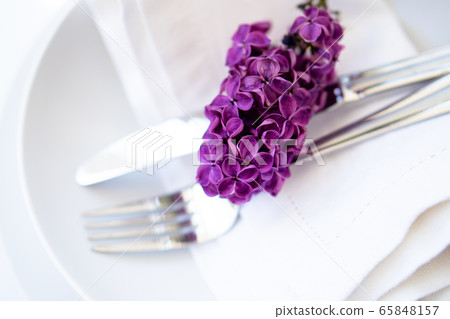 Springtime table setting with lilac branch on white linen napkin 65848157