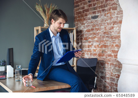 Young man, manager, team led return to work in his office after quarantine, feels happy and inspired Young man, manager, team led return to work in his office after quarantine, feels happy and inspired 65848589