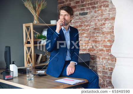 Young man, manager, team led return to work in his office after quarantine, feels happy and inspired Young man, manager, team led return to work in his office after quarantine, feels happy and inspired 65848590