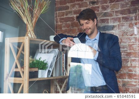 Young man, manager, team led return to work in his office after quarantine, feels happy and inspired Young man, manager, team led return to work in his office after quarantine, feels happy and inspired 65848591
