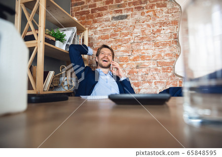 Young man, manager, team led return to work in his office after quarantine, feels happy and inspired Young man, manager, team led return to work in his office after quarantine, feels happy and inspired 65848595