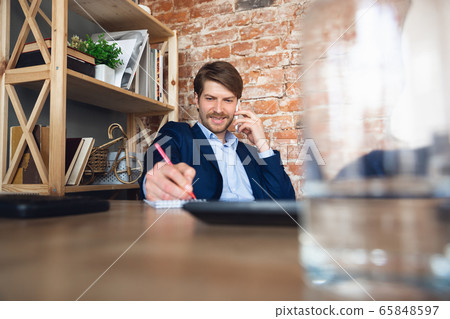 Young man, manager, team led return to work in his office after quarantine, feels happy and inspired Young man, manager, team led return to work in his office after quarantine, feels happy and inspired 65848597