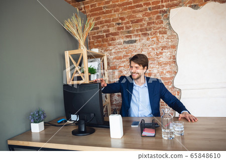 Young man, manager, team led return to work in his office after quarantine, feels happy and inspired Young man, manager, team led return to work in his office after quarantine, feels happy and inspired 65848610