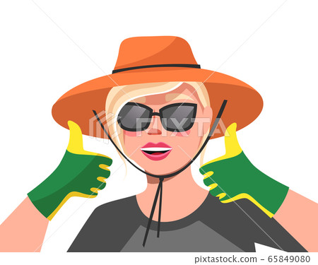 Young happy woman in hat, sunglasses and green garden gloves on her hands is holding her thumb up 65849080