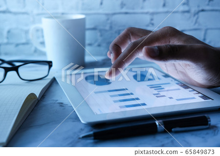 Man hand analyzing chart on digital tablet at office desk Man hand analyzing chart on digital tablet at office desk 65849873