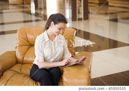 Portrait of busy business woman working on ipad while sitting at sofa. Small business. 65850105